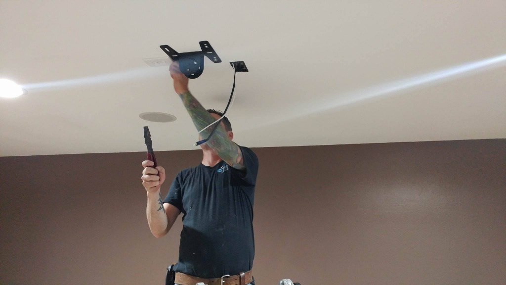Technician wiring an in-ceiling speaker during installation
